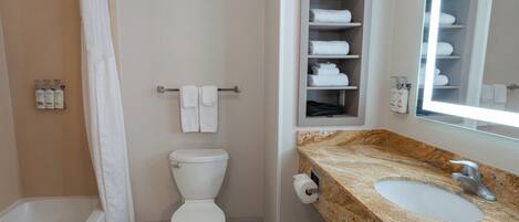 Un baño con bañera, inodoro, lavabo y un perchero con toallas.