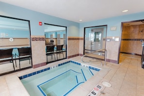 A hotel pool area with a clear view of the pool, a seating area with chairs, and a shower area.