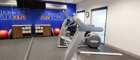 A gym with treadmills, exercise balls, and a wall with motivational text.