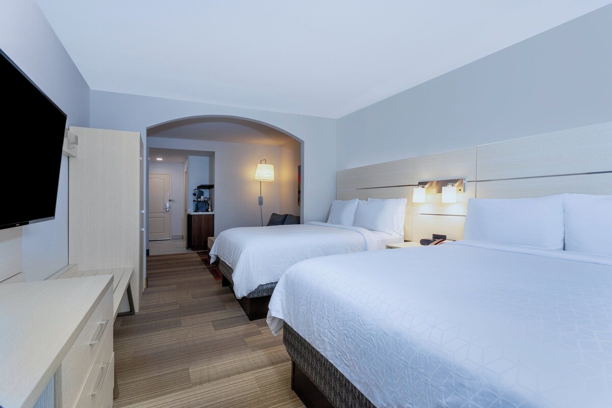 Une chambre d’hôtel avec deux lits, une télévision et un couloir menant à la salle de bain.