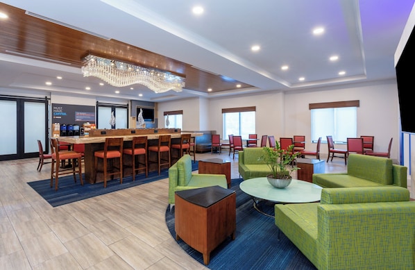 A hotel lobby with a bar area, seating arrangements, and a chandelier. - Holiday Inn Express & Suites, International Drive by IHG (Orlando)
