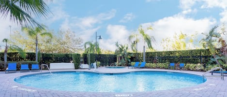 Une piscine avec des chaises bleues et une terrasse dallée.