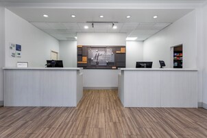 A reception area with two counters, a wooden floor, and a sign for Holiday Inn Express & Suites.