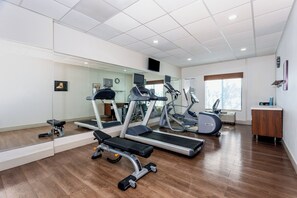 A gym with cardio machines, a bench press, and a mirrored wall. - Holiday Inn Express & Suites, International Drive by IHG (Orlando)