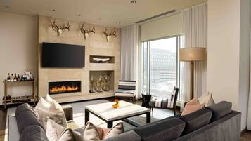 A modern living room with a fireplace, a large flat-screen TV, and a sofa.