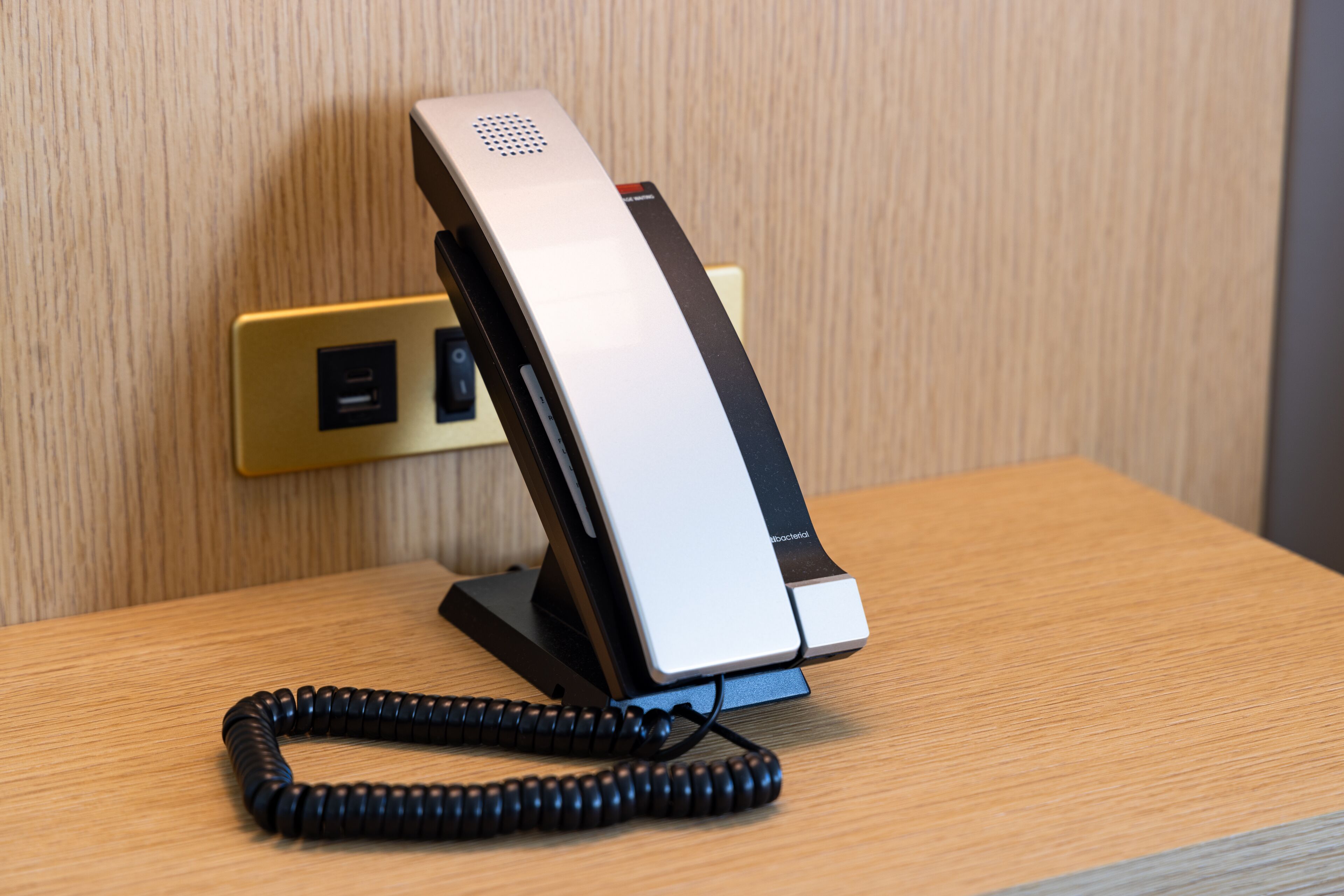 Un teléfono sobre un escritorio con un cable enrollado.