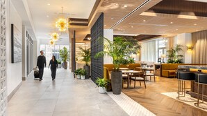 A modern hotel lobby with a spacious layout, featuring a reception desk, seating area, and potted plants. - The Moran CITYCENTRE (Houston)