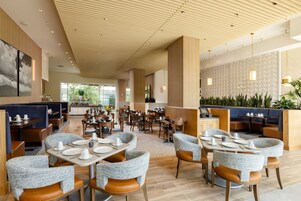 A spacious restaurant with high ceilings, wooden paneling, and a variety of seating arrangements including booths and tables.