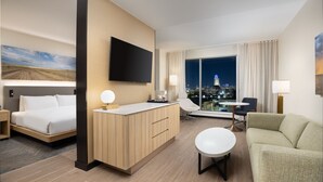 A hotel room with a bed, a desk, a sofa, and a TV. - The Moran CITYCENTRE (Houston)