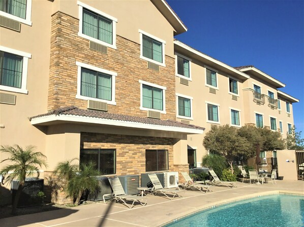 Relax by the pool surrounded by lush greenery and palm trees.