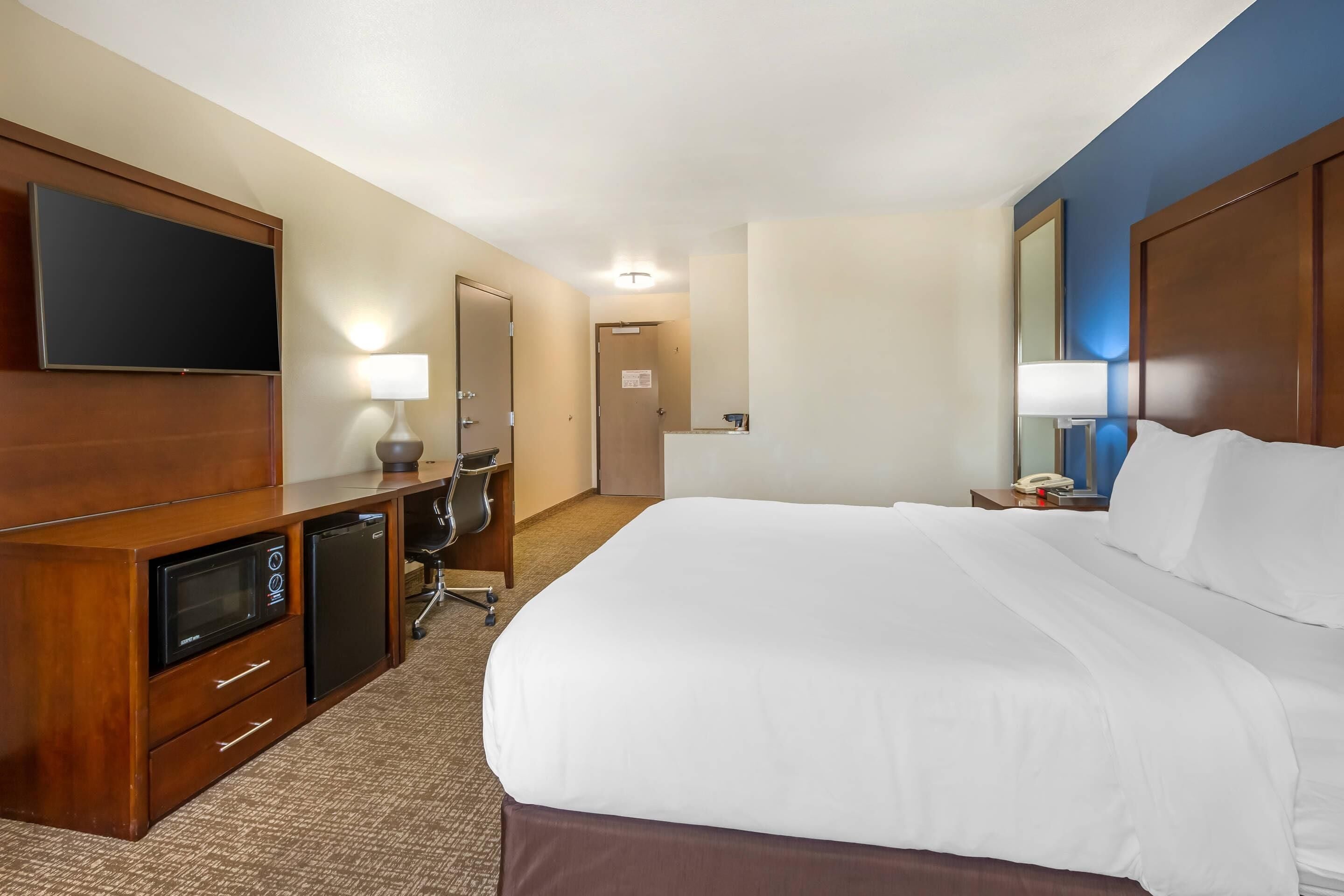 Hotelkamer met een groot bed, een flatscreen televisie, een bureau met lamp en een magnetron.
