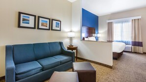 Ein Hotelzimmer mit einem blauen Sofa, einem kleinen Tisch mit einer Lampe, einem Bett und einem großen Spiegel.