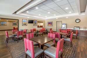 Experience the stylish lobby, featuring a waiting area with tables, chairs, and artwork, alongside a reception desk.
