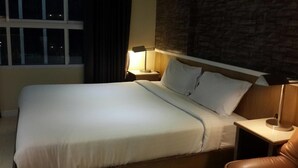 A neatly made bed with white linens, a headboard with a stone-like texture, and two bedside lamps on wooden nightstands.