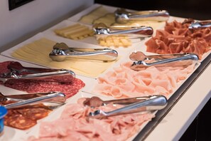 A buffet with various meats and cheeses, including salami, ham, and different types of cheese, arranged on a tray. - H2 Fuenlabrada (Fuenlabrada)