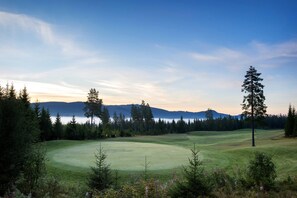 A golf course with a clear view of the surrounding forest and mountains.