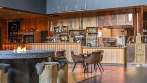 Uma área de bar moderna com uma lareira central, balcão de madeira e assentos com banquetes.