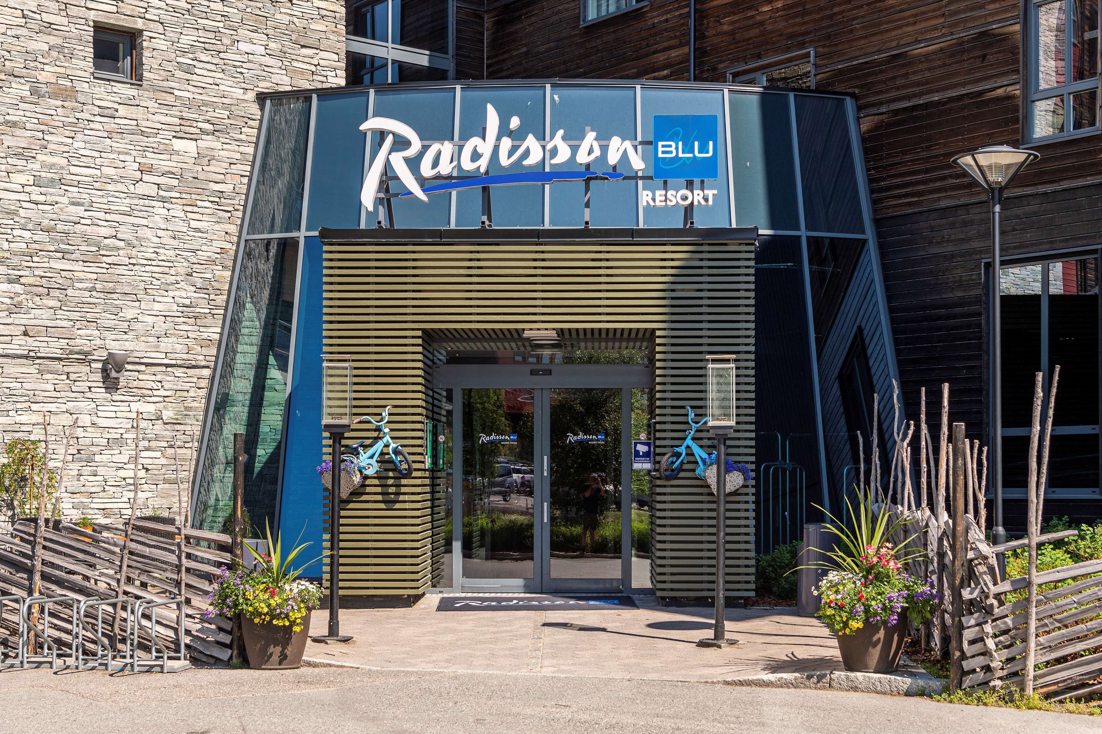 Indgangen til Radisson Blu Resort med en stenfassade, glasdøre og et skilt over døren.