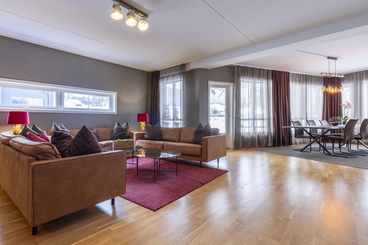 A spacious living area with a leather sofa, coffee table, and dining table set.