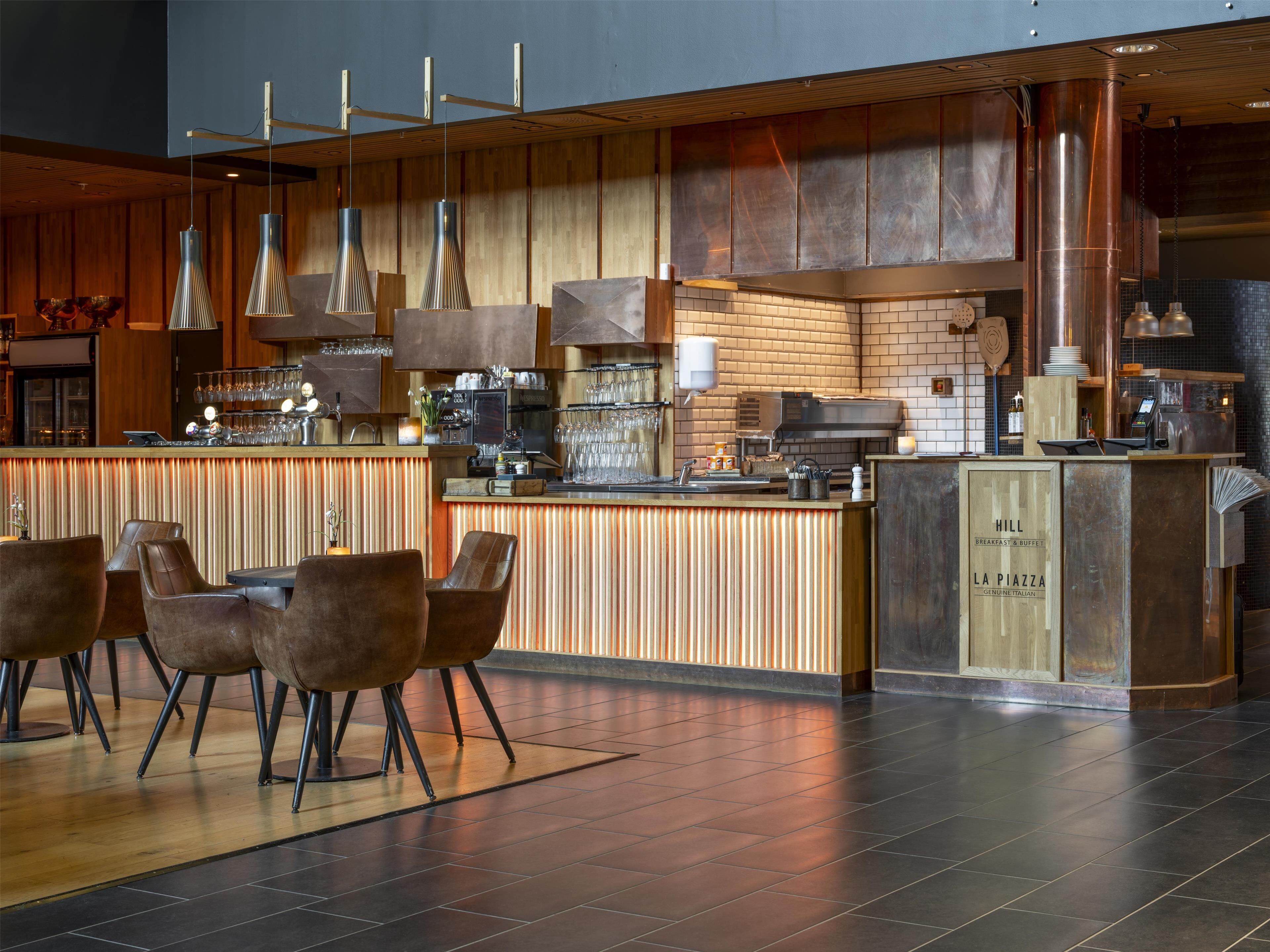 A modern bar area with a wooden counter, bar stools, and hanging pendant lights.