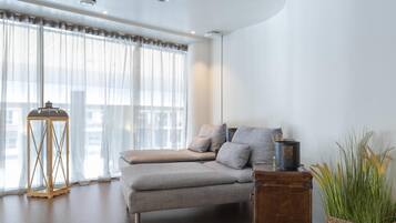 A modern bedroom with a sofa bed, a wooden side table, and a potted plant.