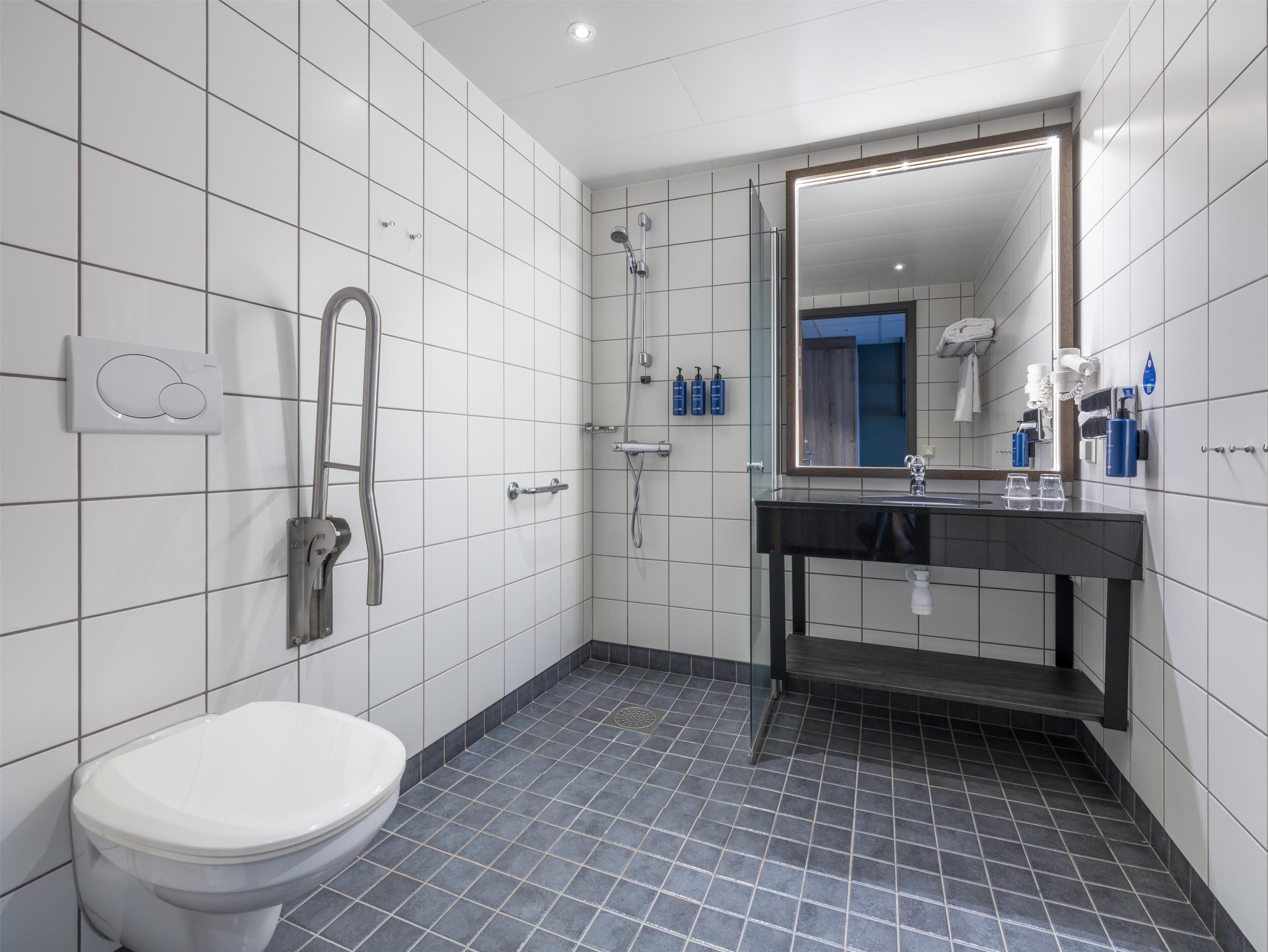 A modern bathroom with a toilet, a shower, and a sink with a mirror.