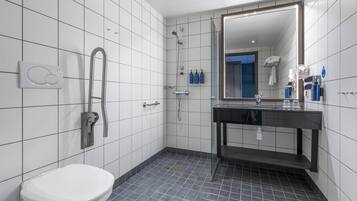 A modern bathroom with a toilet, a shower, and a sink with a mirror.
