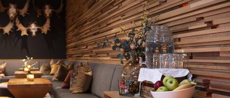 A modern living room with a wooden wall, a grey sofa, a wooden coffee table, and a bowl of fruit on a wooden side table.