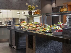 A buffet setup with various food items and a decorative vase.