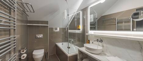 A modern bathroom with a glass-enclosed shower, a white toilet, a built-in sink, and a large mirror.