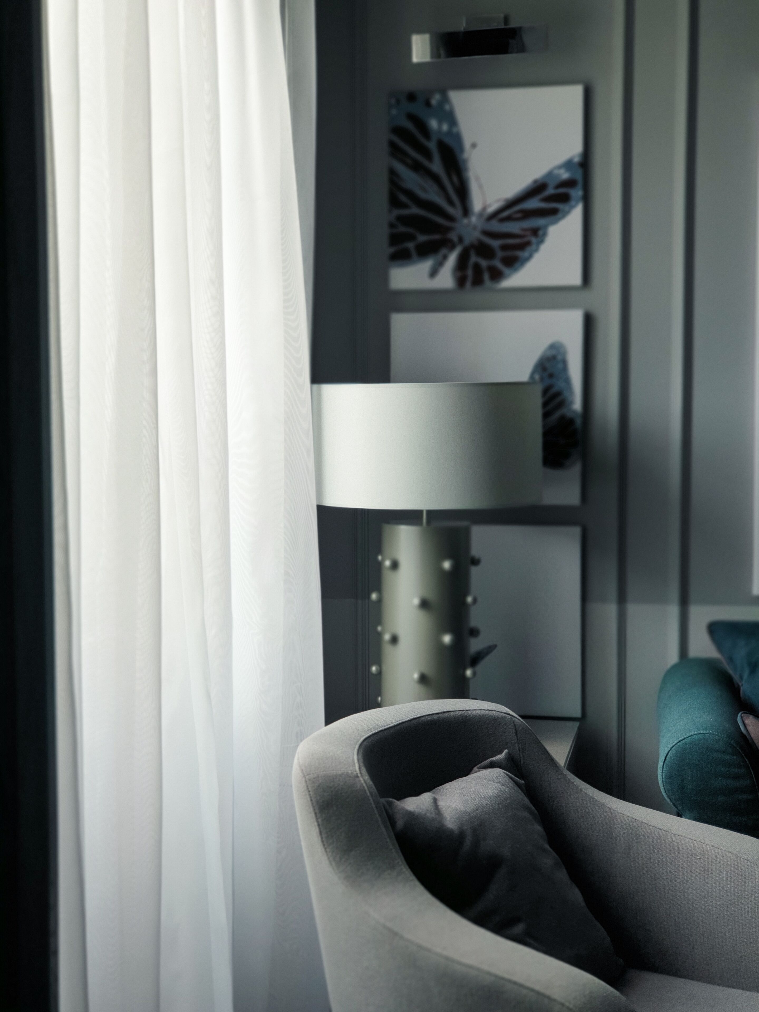 A modern living room with a grey armchair, a floor lamp, and a butterfly wall art piece.