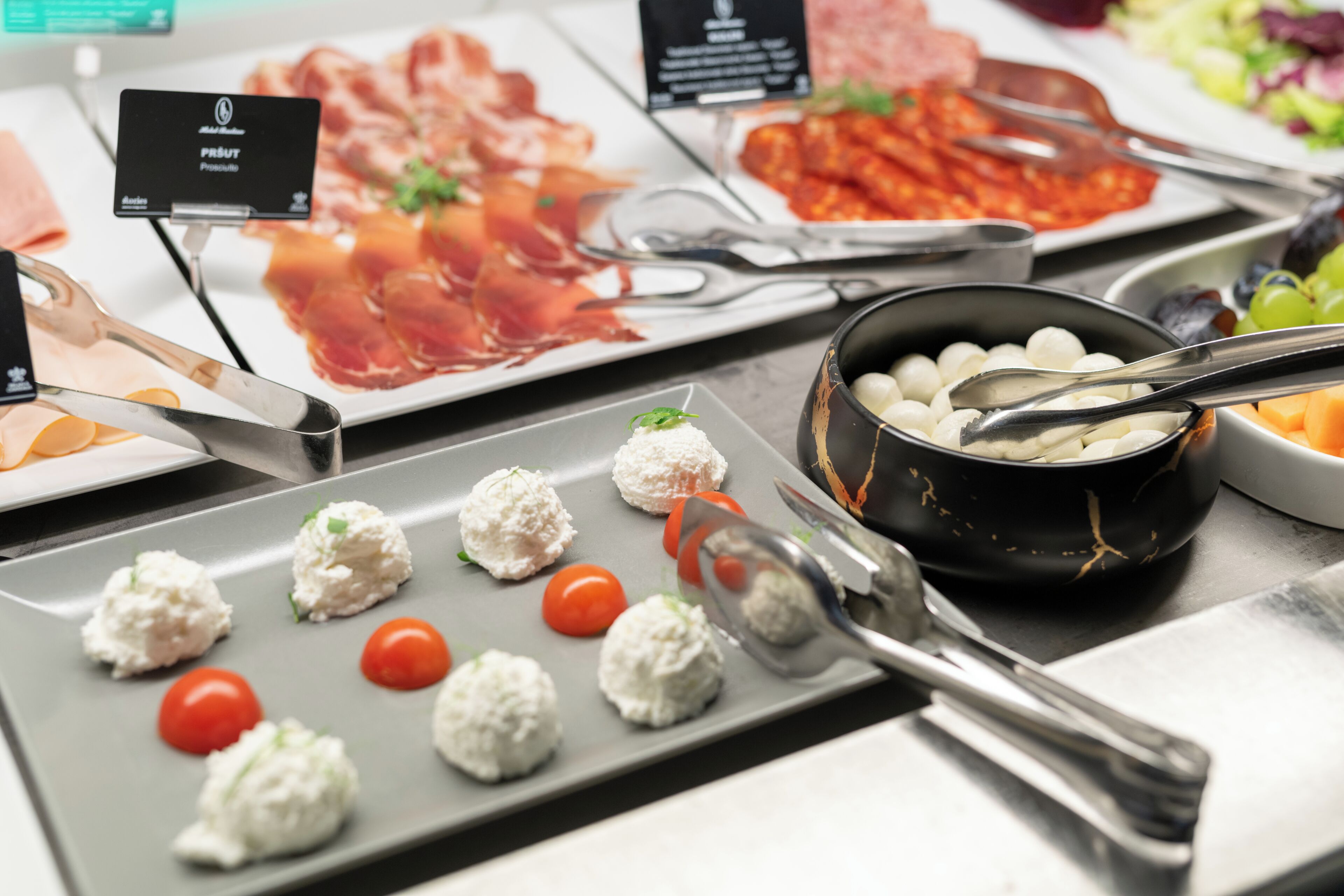 Ein reichhaltiges Buffet mit verschiedenen Speisen, darunter Fleisch, Käse und Gemüse.