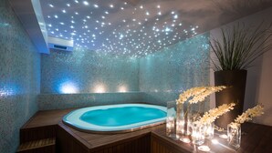 Un área de spa con hidromasaje, asientos de madera e iluminación decorativa.
