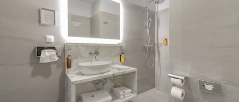 Une salle de bain moderne avec un lavabo en marbre, un grand miroir, une douche et un porte-rouleau de papier toilette.