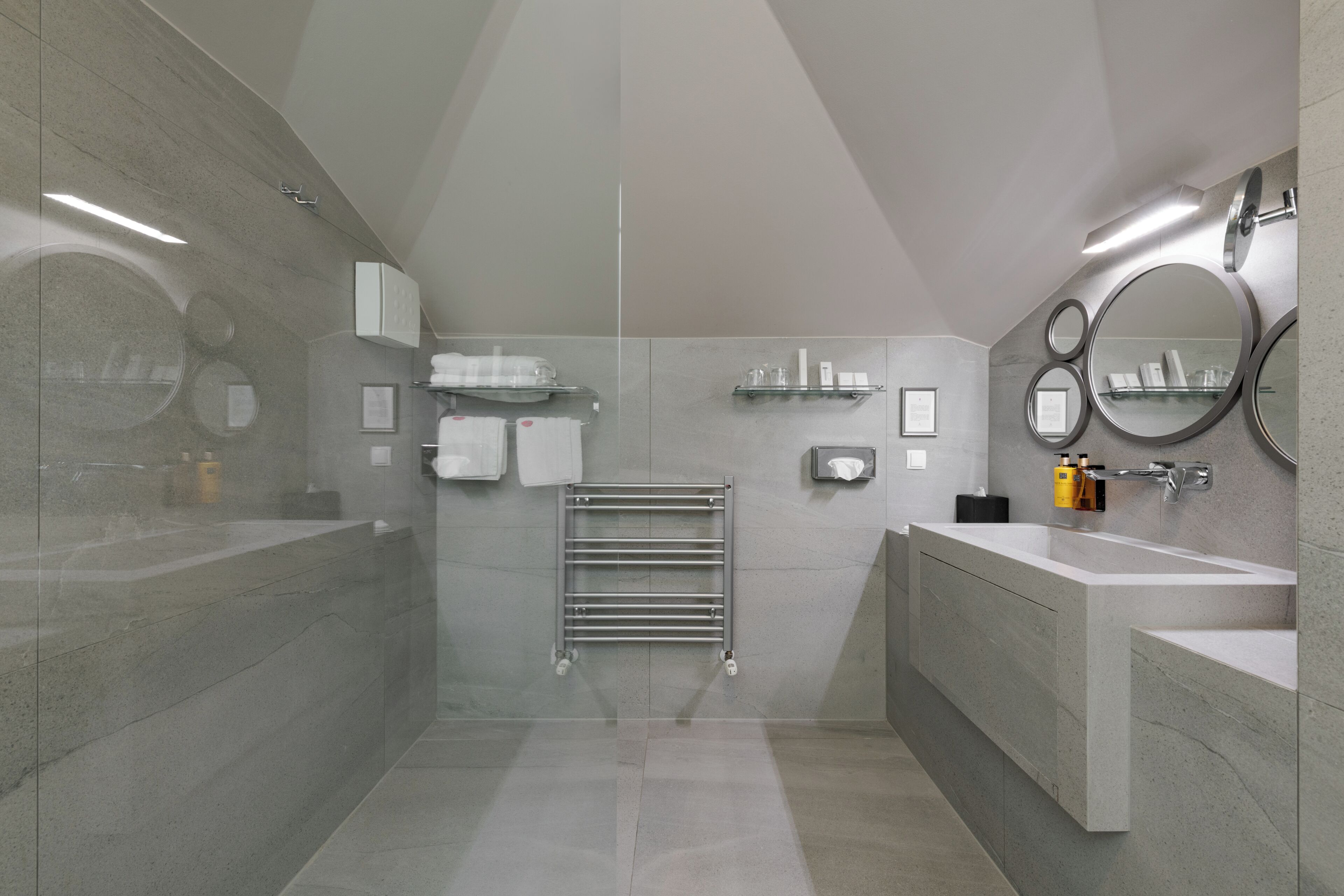 A modern bathroom with a large bathtub, a separate shower area, a vanity with a sink, and a mirror.