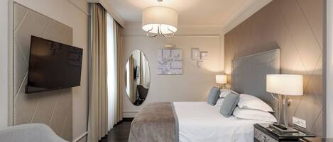 Une chambre d’hôtel moderne dotée d’un grand lit, d’une télévision à écran plat, d’un miroir et d’un bureau avec une lampe.