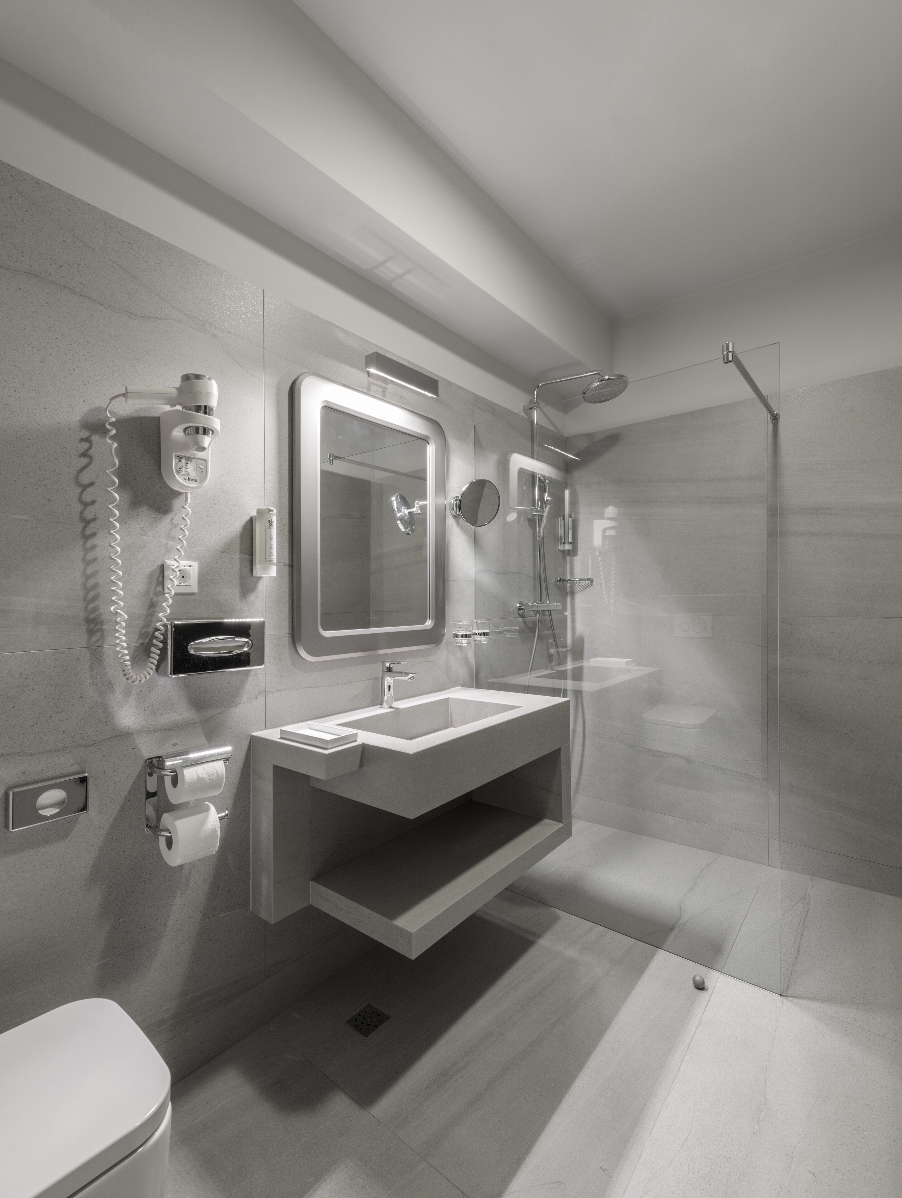 A modern bathroom with a glass shower enclosure, a built-in sink, and a toilet.