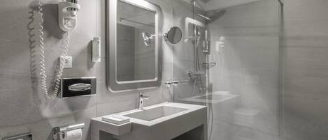 A modern bathroom with a glass shower enclosure, a built-in sink, and a toilet.
