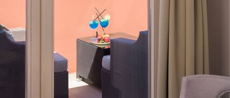A balcony with wicker furniture, a table with a book and headphones, and a view of boats and buildings.