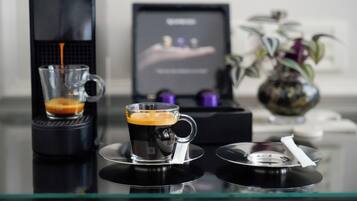 A coffee machine dispensing coffee into a glass cup on a glass table.