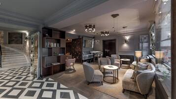 Et moderne interiør med trappe, reoler, sofaer og et mønstret gulv.