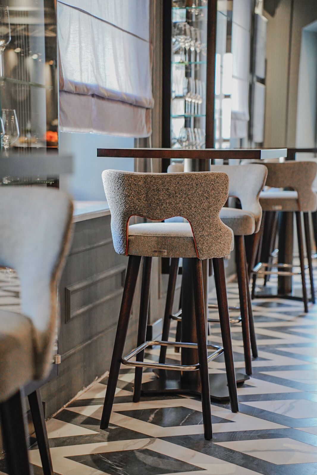 Una zona de bar con taburetes altos y un suelo con diseño.