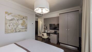 A hotel room with a bed, desk, TV, wardrobe, and artwork.