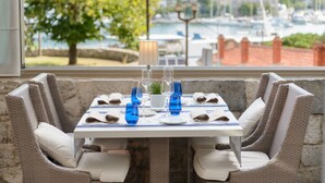 Una mesa de comedor dispuesta con cristalería azul, servilletas blancas y una pequeña planta en maceta.