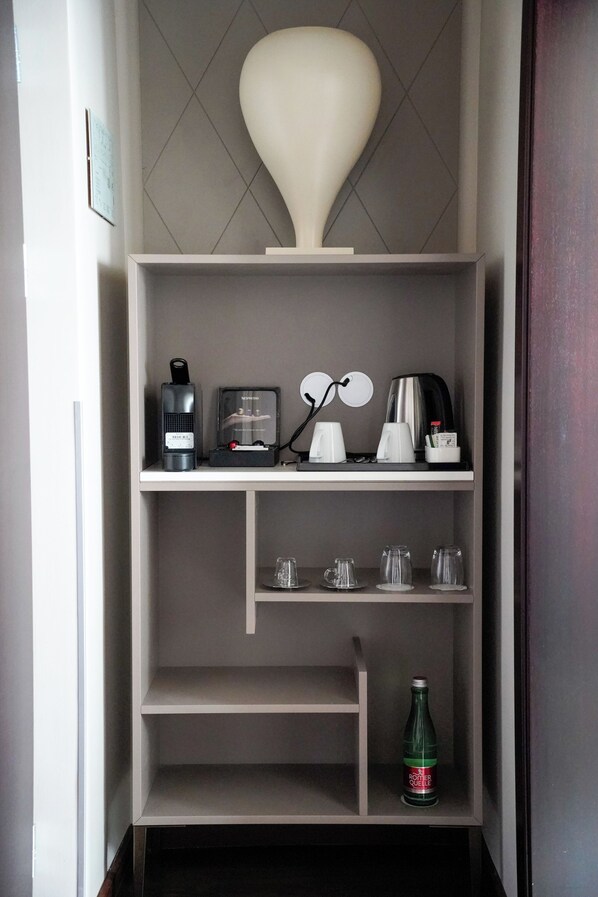 Una kitchenette con cafetera, hervidor y una botella de refresco.
