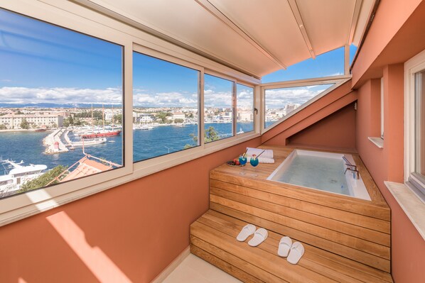 Un balcón con una bañera de madera y vistas al puerto.