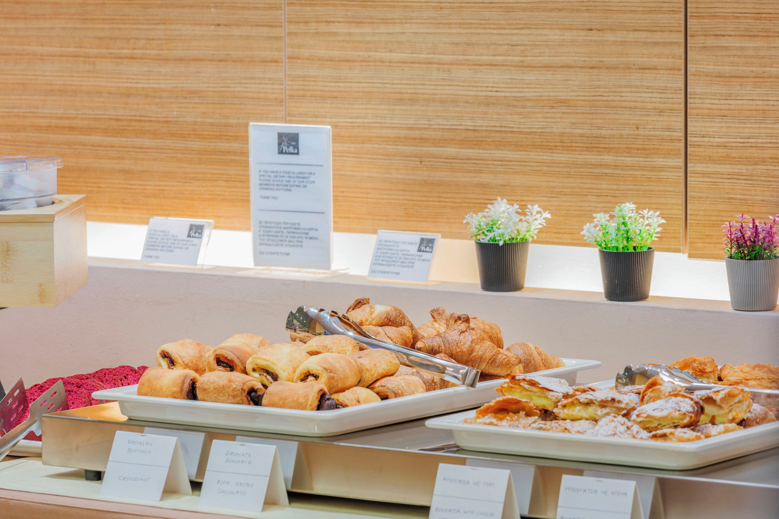 Un buffet proposant une variété de viennoiseries et de desserts, notamment des croissants et des pâtisseries feuilletées, présentés sur des plateaux avec des étiquettes.
