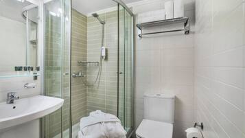 Een moderne badkamer met een glazen douchecabine, een witte wastafel en een toilet.