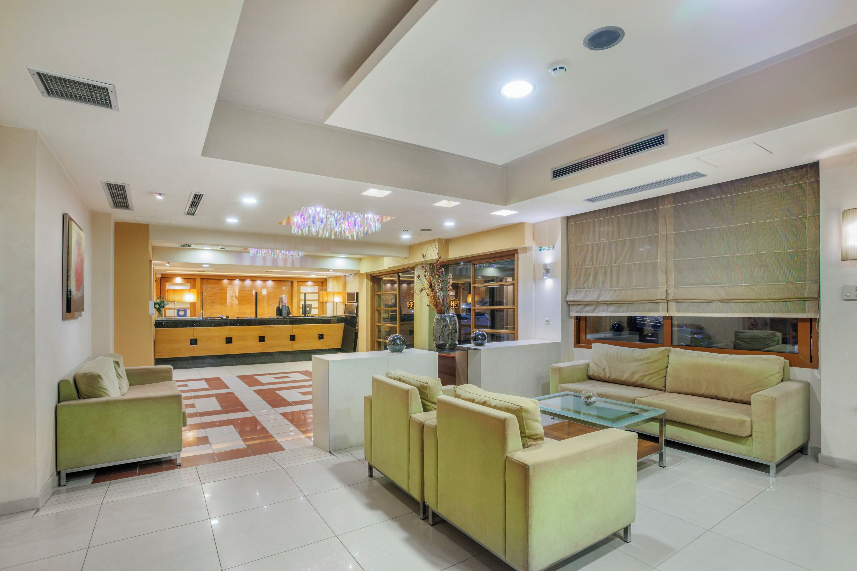 Eine Hotelhalle mit einer Rezeption, Sofas, einem Couchtisch und einem dekorativen Kronleuchter.