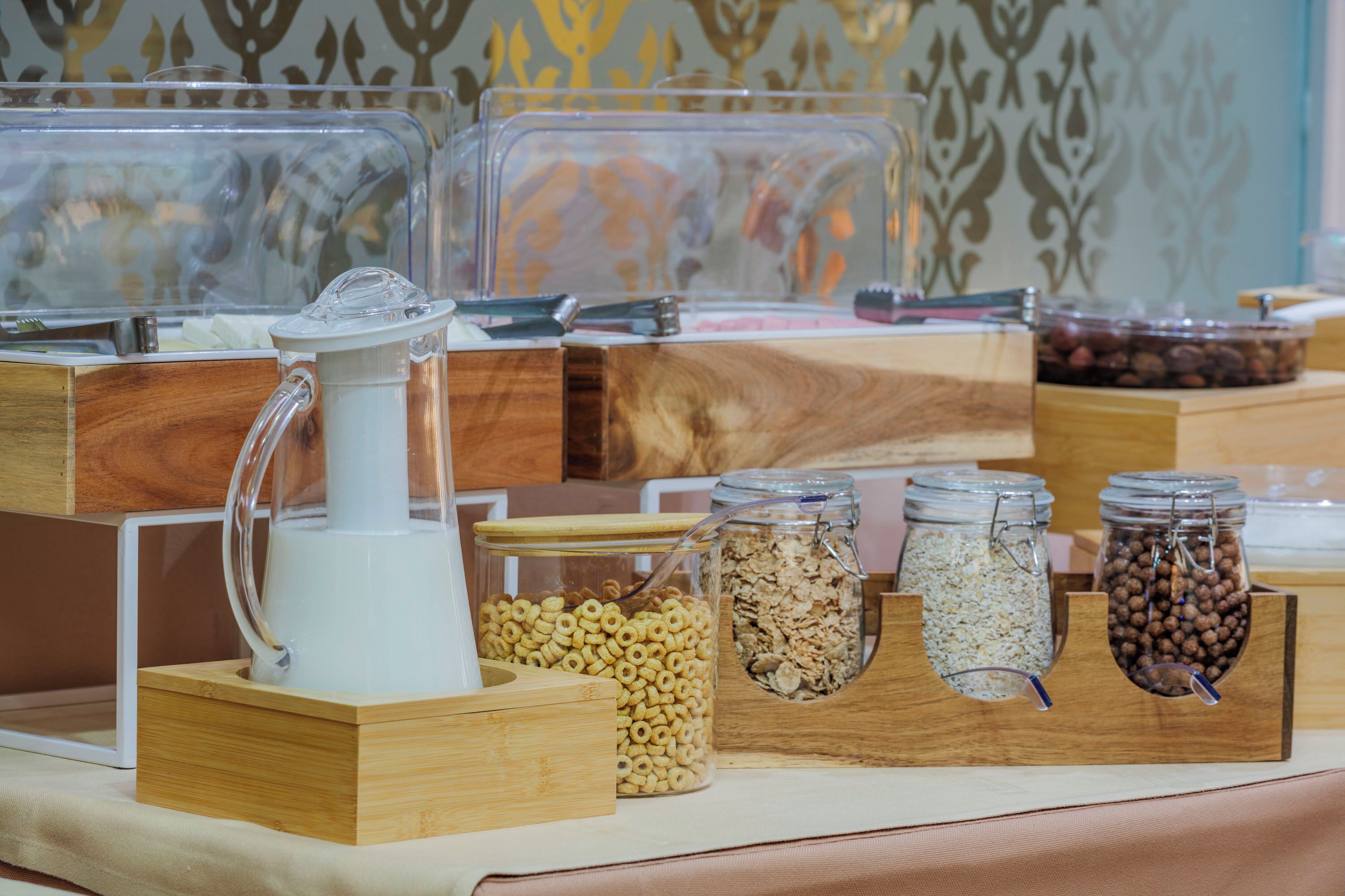 A buffet setup with various food items in containers, including cereals and nuts, arranged on wooden stands.